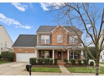 Charming two-story brick home featuring a covered front porch and well-maintained landscaping at 8806 Cool Meadow Dr, Huntersville, NC 28078