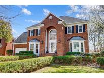 Stately brick home featuring an arched entryway, manicured landscaping, and black shutters at 9239 Silver Pine Dr, Charlotte, NC 28277