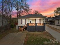 Charming home with a welcoming front porch and updated landscaping, featuring a unique, colorful sky at sunset at 133 2Nd Ave, China Grove, NC 28023