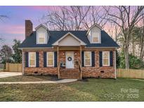 Charming brick home featuring a welcoming front porch, dormer windows, a well-manicured lawn, and mature trees at 1815 Townes Ct, Rock Hill, SC 29730