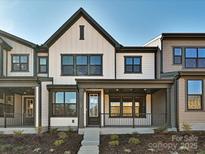 Modern townhome showcasing board and batten siding, black framed windows, and a welcoming covered porch at 209 Halemarg Dr, Belmont, NC 28012