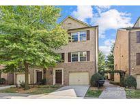 Charming brick two-story townhouse with attached garage, beautiful tree, and manicured front yard at 225 Lincoln St, Charlotte, NC 28203