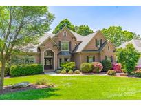 Beautiful brick home featuring professional landscaping and a welcoming front lawn at 13358 Bally Bunnion Way, Davidson, NC 28036