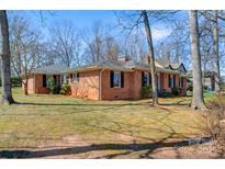 Charming brick home with mature trees and inviting curb appeal under a clear blue sky at 1751 5Th Ne St, Hickory, NC 28601