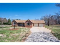 Charming brick ranch home with an attached two-car garage and a well-manicured lawn at 1922 Dogwood Flower Ln, Lincolnton, NC 28092