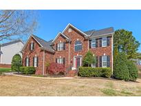 Stately two-story brick home featuring manicured landscaping and a welcoming red front door at 6141 Abergele Ln, Matthews, NC 28104