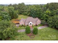 Charming single-story brick home with a well-manicured front yard, mature trees, and a welcoming entryway at 105 Partridge Bluff Ne Dr, Concord, NC 28025