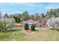 Charming single-story brick home with a meticulously maintained front yard and a vibrant blue front door at 105 Partridge Bluff Ne Dr, Concord, NC 28025