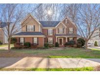 Charming two-story brick home with manicured lawn, complemented by mature trees and a welcoming front porch at 16115 Chiltern Ln, Huntersville, NC 28078