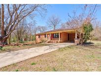 Charming brick home featuring a covered carport and cozy front porch, nestled on a spacious lot with mature trees at 200 South Fork Dr, Shelby, NC 28152