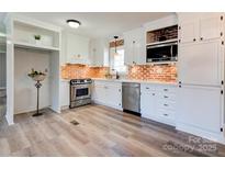Well-lit kitchen featuring brick backsplash, white cabinets, and stainless steel appliances at 200 South Fork Dr, Shelby, NC 28152