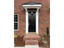 Inviting brick home featuring a black front door with a white frame and covered entrance and manicured landscaping at 447 Beacon Nw St, Concord, NC 28027