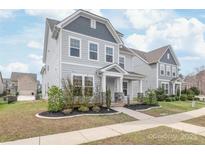 Charming two-story home with light gray siding, a covered porch, and manicured landscaping at 3017 Woodlands Creek Dr, Monroe, NC 28110