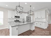 Modern kitchen with granite counters, stainless appliances, white cabinets, and stylish pendant lighting at 3017 Woodlands Creek Dr, Monroe, NC 28110