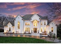Stately white home with a symmetrical facade, arched windows, and manicured lawn under a vibrant sky at 4335 Piper Glen Dr, Charlotte, NC 28277