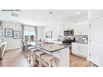 Bright kitchen features stainless appliances, white cabinetry and an island with bar seating at 469 Court House Ave, York, SC 29745