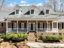 Charming brick home with a welcoming front porch, white columns, black shutters, and well-manicured landscaping at 501 Colonels Ct, Clover, SC 29710