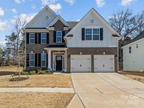 Beautiful two-story home featuring a two-car garage, brick and white siding, and a well-maintained front yard at 5056 Blue Serenity Ct, Denver, NC 28037