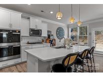 Bright, open kitchen with quartz countertops, modern appliances, and a cozy breakfast bar with seating at 5056 Blue Serenity Ct, Denver, NC 28037