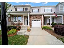 Charming townhome featuring a one car garage, stone accents, and a covered front porch with seating at 769 River Park Rd, Belmont, NC 28012