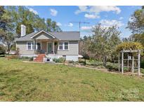 Charming one story home featuring a welcoming front porch, landscaped yard, and lovely blue sky at 10633 Hwy 52 Hwy, Rockwell, NC 28138