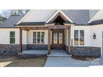 Inviting home entrance featuring a wooden door, stone accents, and stylish architectural details at 3732 Whitney Ne Dr, Hickory, NC 28601