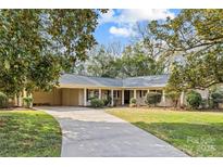 Charming single-story brick home with a well-manicured lawn and mature landscaping at 6014 Glenridge Rd, Charlotte, NC 28211
