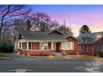 Charming brick home featuring a welcoming front porch with white pillars and a beautifully landscaped yard at dusk at 609 2Nd Ne St, Hickory, NC 28601