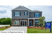 Charming two-story home with stone accents, gray siding, and a well-manicured lawn at 1320 Secrest Commons Dr, Monroe, NC 28112