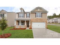 Charming two-story home with a brick facade, attached garage, covered porch, and manicured front lawn at 1325 Secrest Commons Dr, Monroe, NC 28112