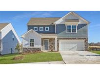 Charming two-story home features a stone facade, attached two-car garage and manicured front lawn at 1825 Broom Maker Dr, Bessemer City, NC 28016