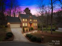 Inviting two-story brick home featuring manicured landscaping and a well-lit driveway for a warm nighttime appeal at 2020 Fairchelsea Way, Matthews, NC 28105
