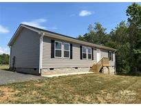 Charming home featuring gray siding, black shutters and well-maintained landscaping at 565 Perry Rd, Troutman, NC 28166