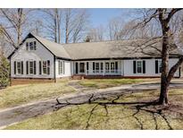Charming home featuring black shutters, complemented by a well-manicured lawn and long driveway at 10101 Woodview Cir, Charlotte, NC 28277