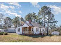 Charming home featuring a cozy front porch, white siding, and a contrasting dark metal roof at 15 Gumtree St, Wadesboro, NC 28170