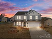 Charming two-story home with a covered porch and a two-car garage, showcasing its inviting curb appeal at 603 Smokehouse Ln, Albemarle, NC 28001