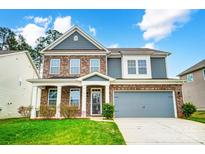 Two-story home featuring a brick and gray siding exterior, a two-car garage, and a well-manicured lawn at 670 Belle Grove Dr, Clover, SC 29710