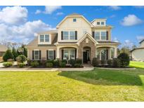 Beautiful two-story home with manicured lawn, stone accents, and welcoming front porch with tasteful landscaping at 1022 Torrens Dr, Monroe, NC 28110