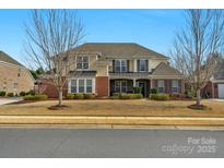 Inviting two-story home featuring a brick facade, manicured lawn, and mature trees on a sunny day at 10415 Waxhaw Manor Dr, Waxhaw, NC 28173