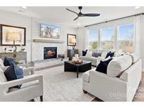 Bright living room with fireplace, large windows, ceiling fan, and modern decor at 173 Holsworthy Dr, Mooresville, NC 28115