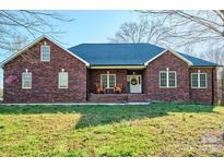 Charming brick home with rocking chairs on the porch, an American flag, and a well-manicured lawn at 28926 Hartsell Rd, Albemarle, NC 28001