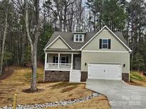 Inviting two-story home featuring a covered porch, attached garage, and classic design elements nestled amongst mature trees at 3667 Travertine Dr, Lancaster, SC 29720