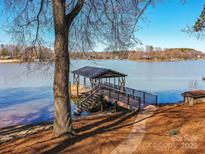 View of private boat dock with covered area on lake with trees and blue sky in the background at 4046 Rhynland Dr, Sherrills Ford, NC 28673