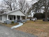 Charming single story home featuring a covered porch, well-kept lawn, and detached garage at 412 E Ross Grove Rd, Shelby, NC 28150