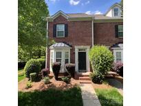 Charming brick townhome with a black front door, manicured landscaping, and bay window at 645 Beaty St, Davidson, NC 28036