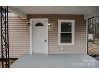 Inviting front entrance with a white door, decorative window, and modern wall-mounted sconces at 176 Gravel Hill Ct, Taylorsville, NC 28681