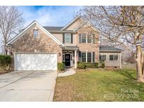 Charming two-story brick home with a well-manicured lawn and attached two-car garage on a sunny day at 303 Basswood Ct, Clover, SC 29710