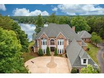 Stunning waterfront home featuring a circular driveway, brick facade, bay windows, and mature landscaping at 3106 47Th Avenue Ne Ln, Hickory, NC 28601