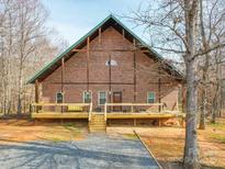 Inviting brick home featuring a charming front porch and well-maintained landscaping at 5687 Putuptoe Pl, Norwood, NC 28128