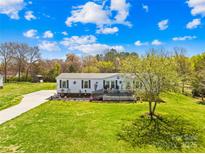 Charming single-story home featuring a cozy front deck, well-manicured lawn, and a scenic country setting at 590 County Line Rd, Stony Point, NC 28678